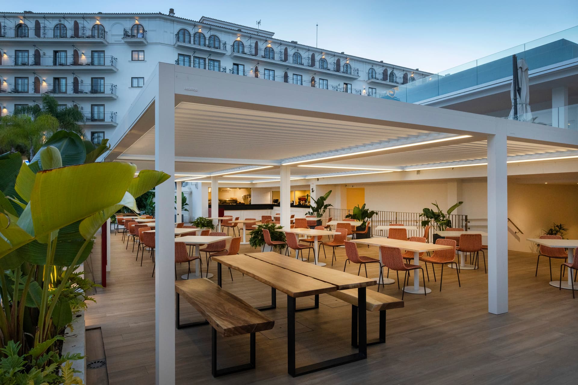 Terrassenüberdachung aus Aluminium mit Lamellen in heller Ausführung über modernem Außenbereich mit zitplaatsen