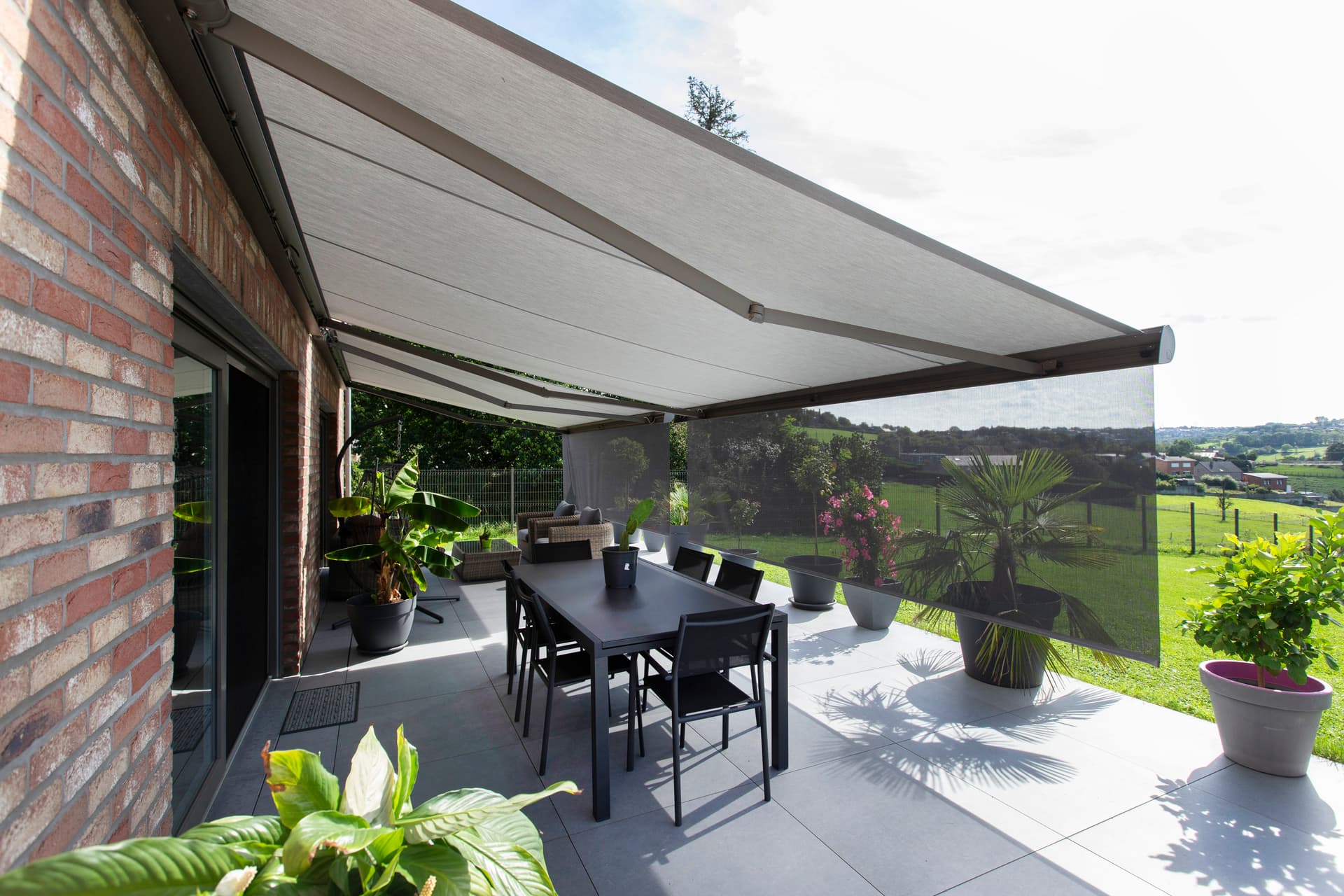 Pergola Brustor con lamelle orientabili, illuminazione LED integrata, screen ZIP e riscaldatori da terrazza che creano una zona pranzo esterna protetta