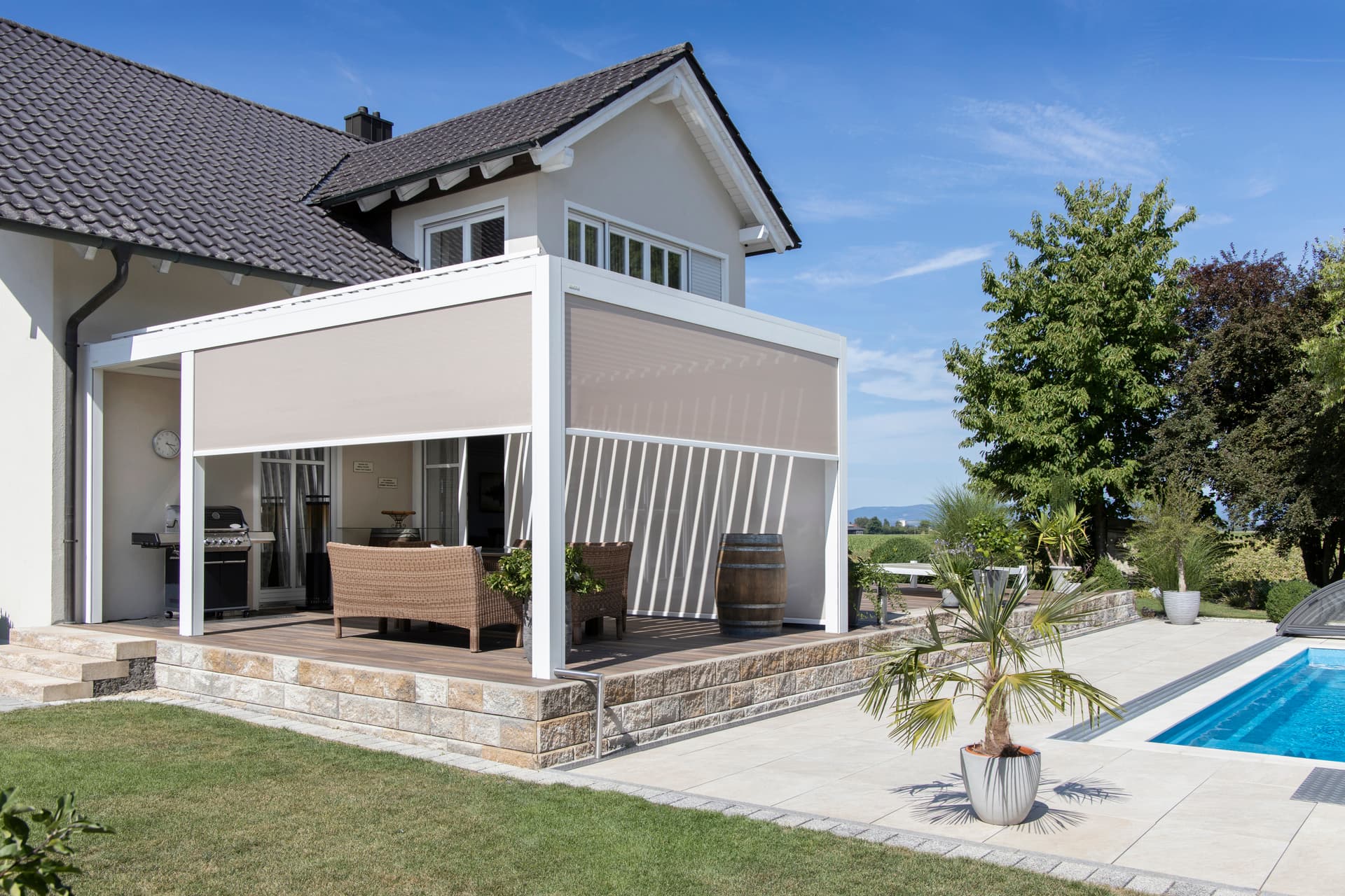 Pergola Brustor con lamelle orientabili, illuminazione LED integrata, screen ZIP e riscaldatori da terrazza che creano una zona pranzo esterna protetta