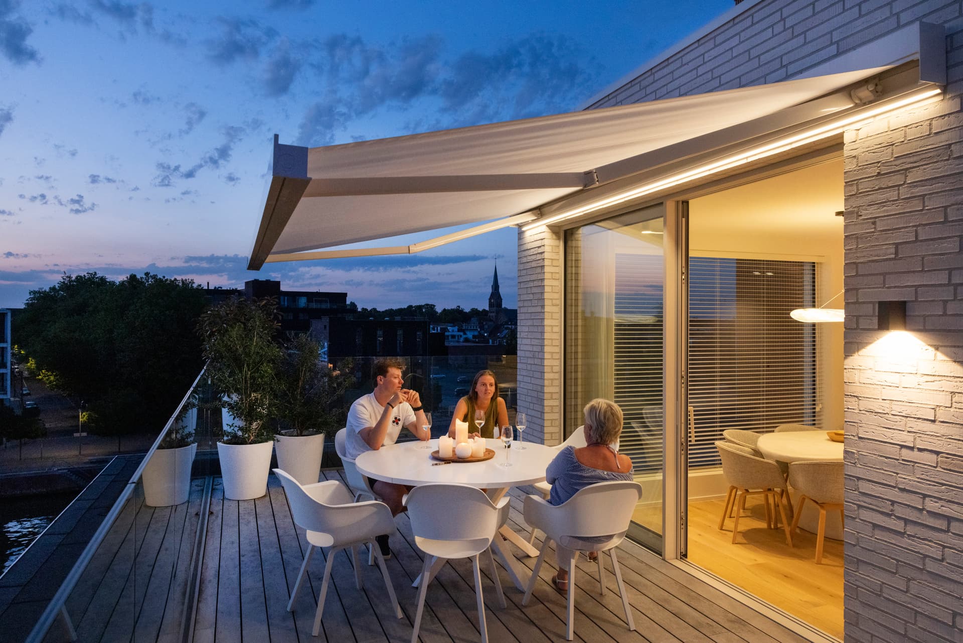 The family is enjoying a drink on the rooftop terrace under an awning with LED strip lights