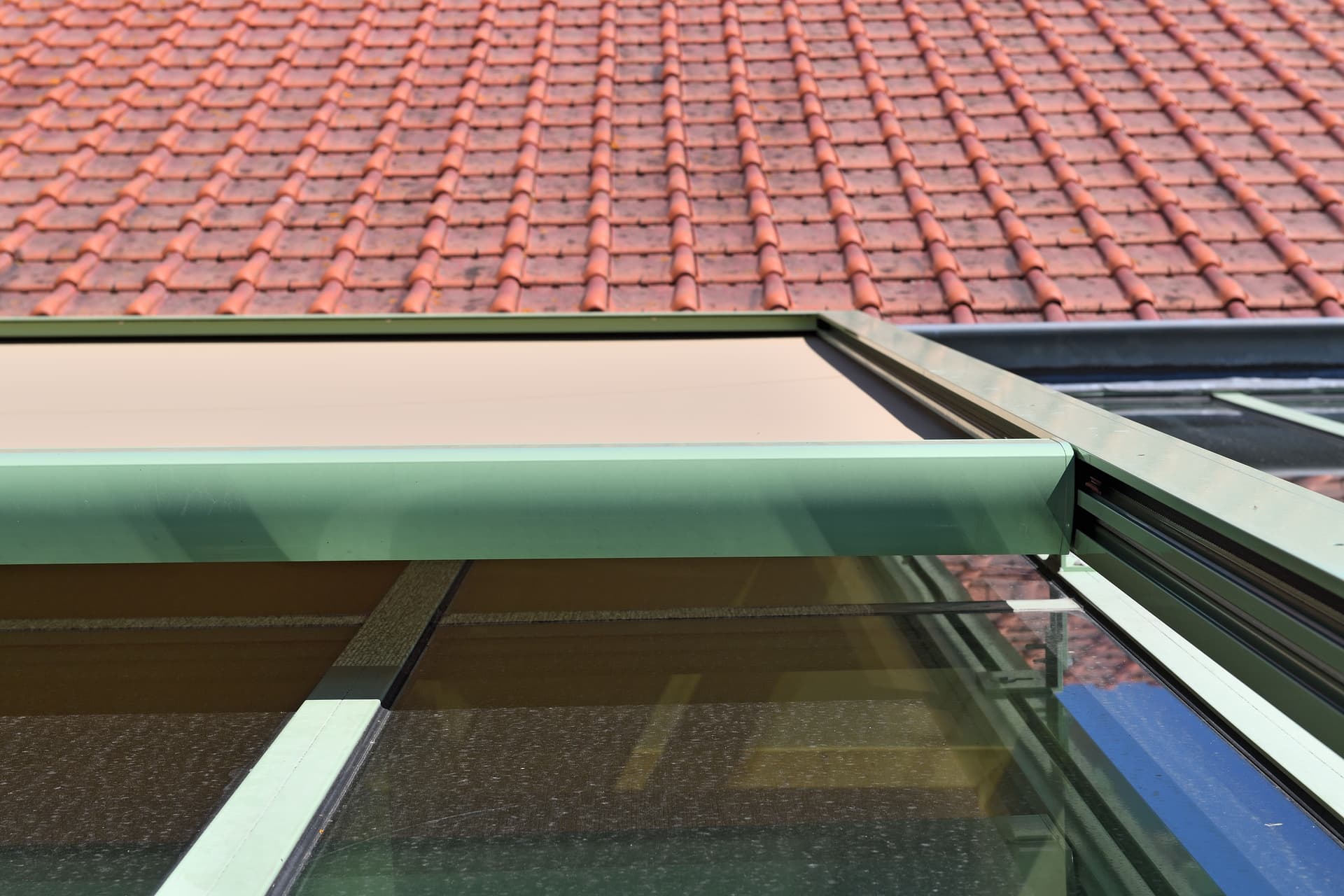 Close‑up of the Brustor B128 conservatory awning casing mounted above a large glass veranda roof, providing wind‑resistant exterior shading
