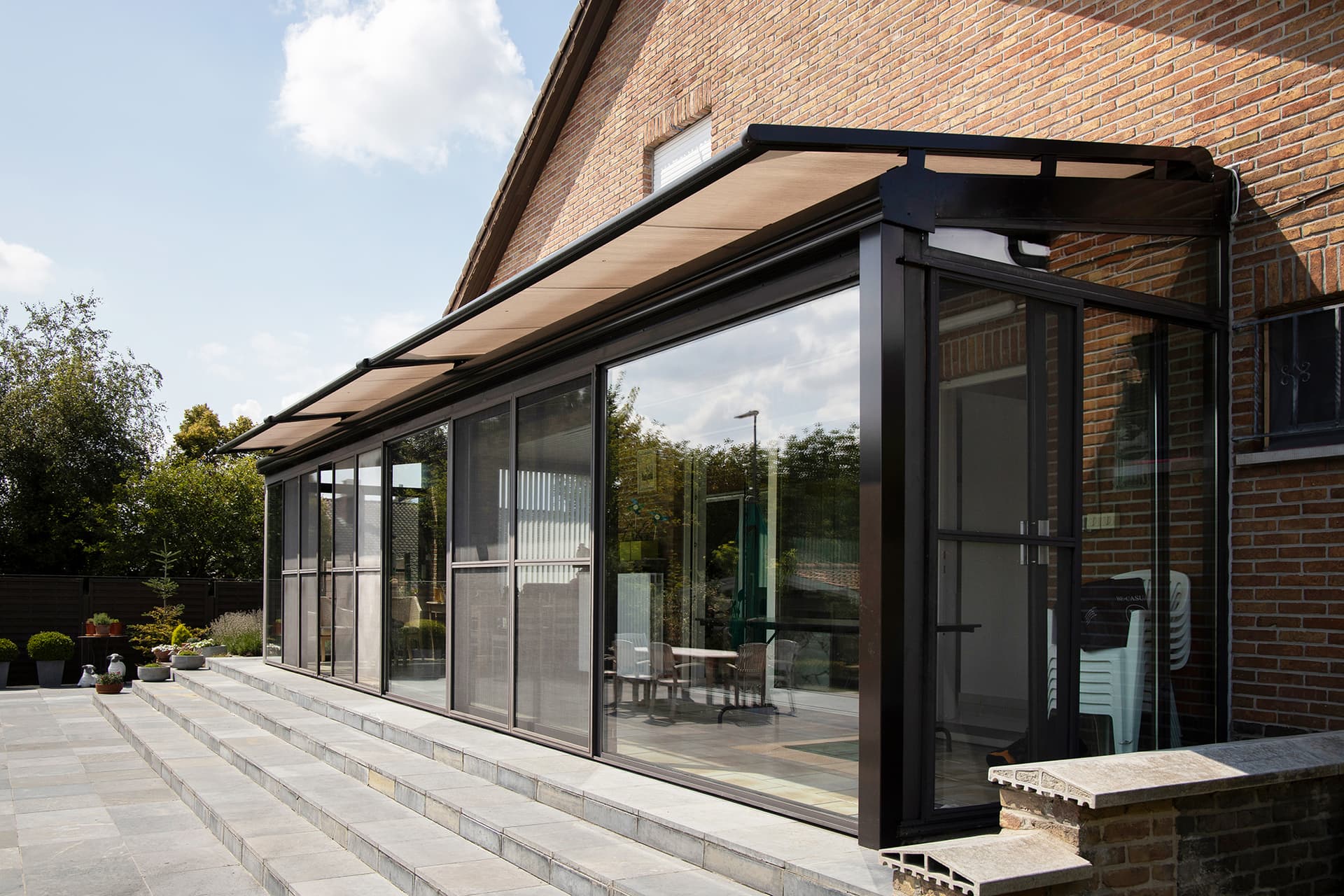 Brustor B126 conservatory awning mounted above a rectangular glass veranda roof providing exterior sun protection along the full structure